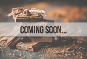 Des morceaux de tablette de chocolat noir empilés sur une table et un bandeau au premier plan où il est écrit "Coming soon".